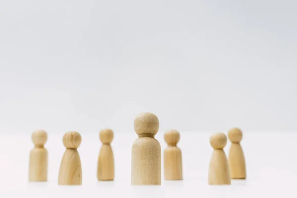 Small group of separated people seen from above represented anonymous with wooden figures on white background.