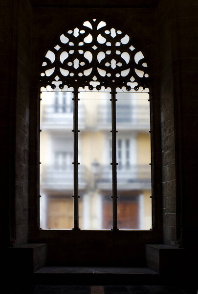 Gothic style stone window in a historic building in Valencia, from inside with a dark atmosphere.
