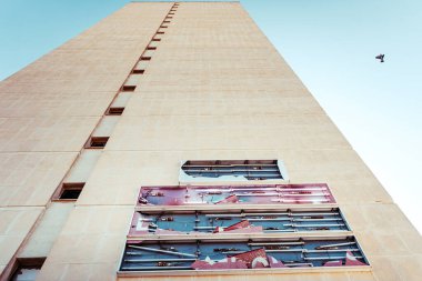 Terk edilmiş bir otel binasının ön cephesi gün boyunca camları kırık, basit çizgileri var..