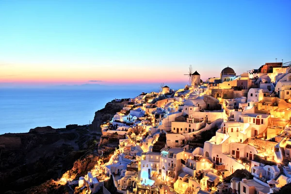 Iluminada aldeia de Oia ao pôr do sol na ilha de Santorini Grécia — Fotografia de Stock