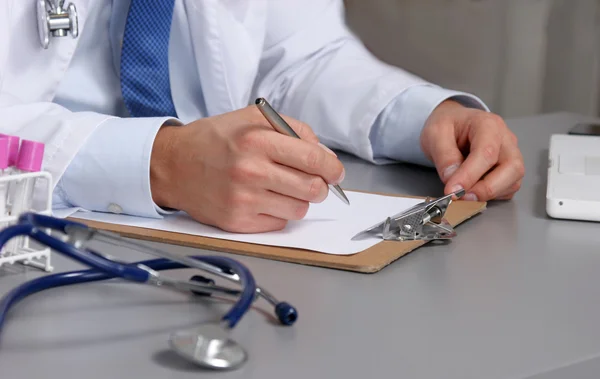 Médico masculino escrever na mesa com tubo de ensaio — Fotografia de Stock