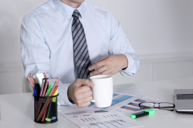 İş adamı büro masasında kahve molası veriyor.