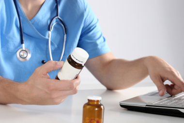 Masada oturan ve şişe tutan erkek doktor