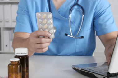 Masada oturan ve şişe tutan erkek doktor