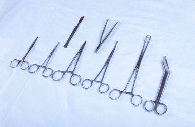 Dört farklı paslanmaz çelik cerrahi forseps ve beyaz arka plan üzerinde izole neşter yakın çekim