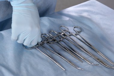 Doktor eller dört farklı paslanmaz çelik cerrahi forseps ve beyaz arka plan üzerinde izole neşter
