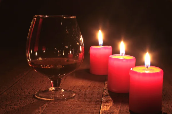 Composición navideña con coñac de vidrio, caja de regalo y vela sobre mesa de madera —  Fotos de Stock