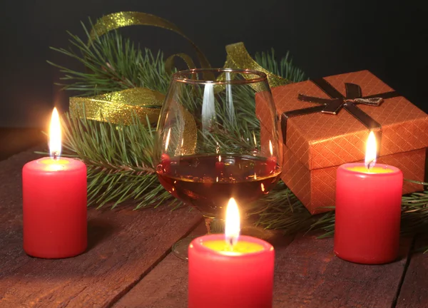 Χριστουγεννιάτικη σύνθεση με ποτήρι κονιάκ, δώρο κουτί και λαμπάδα ξύλινο τραπέζι — Φωτογραφία Αρχείου
