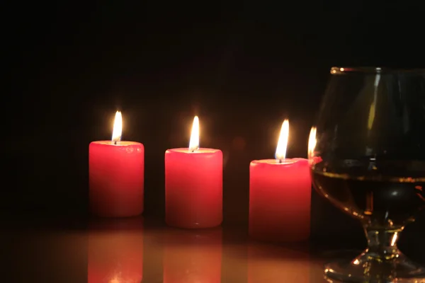 Foto natale vetro cognac e candela su sfondo nero — Foto Stock