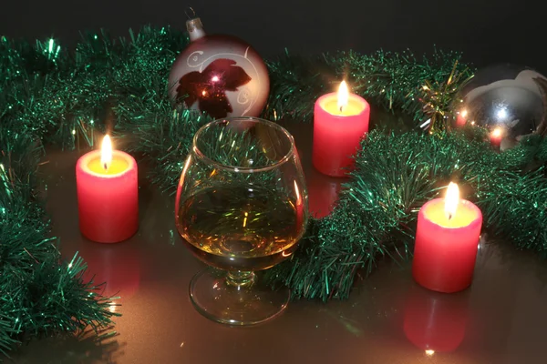 Foto natale vetro cognac e candela su sfondo nero — Foto Stock