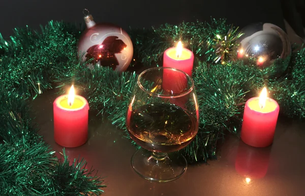 Foto natale vetro cognac e candela su sfondo nero — Foto Stock