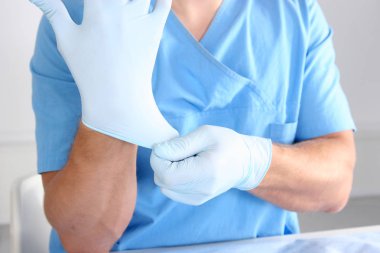 Mavi steril cerrahi eldiven üzerinde koyarak doktor