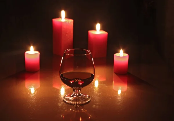 Composizione natalizia foto vetro cognac e candela su sfondo nero — Foto Stock