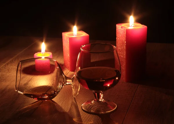 Vaso de coñac y vela roja sobre fondo de madera — Foto de Stock