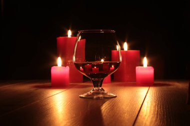 konyak ve kırmızı mum ahşap arka plan üzerinde bardak