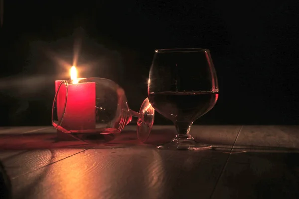 Vetro di cognac e candela rossa su fondo di legno — Foto Stock