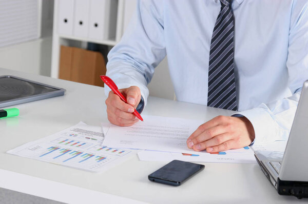 Веселый молодой бизнесмен сидит за столом с ноутбуком и растягивается в офисе
