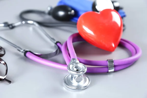 Stethoskop mit rotem Herz auf hellem Hintergrund — Stockfoto
