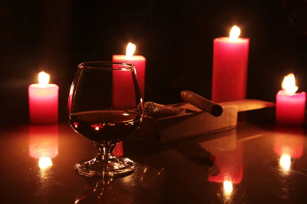 Vaso de brandy o coñac y vela sobre la mesa de madera —  Fotos de Stock