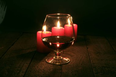 Bardak brendi veya konyak ve ahşap masa mum