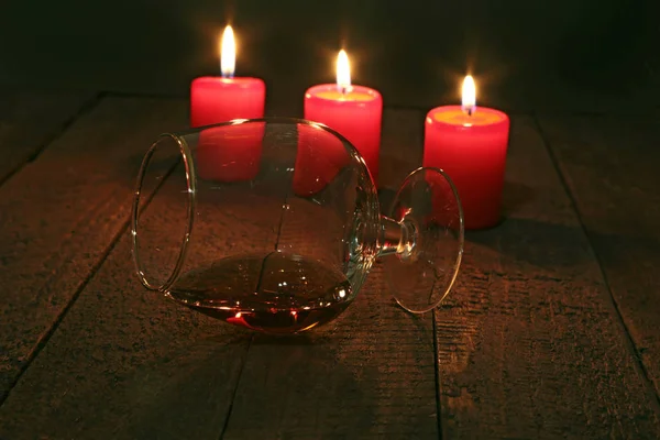 Склянка бренді або коньяку і свічки на дерев'яному столі — стокове фото