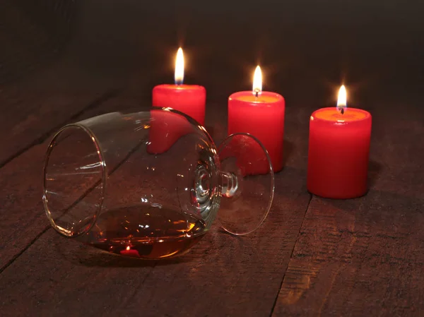 Glass of brandy or cognac and candle on the wooden table — Stock Photo, Image