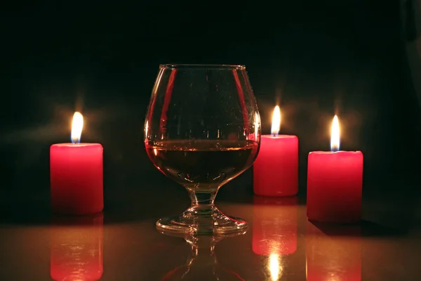 Bicchiere di brandy o cognac e candela sul tavolo di legno — Foto Stock