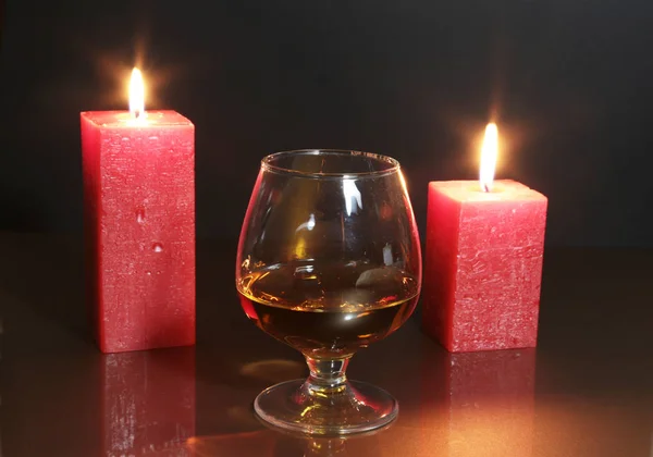 Bicchiere di brandy o cognac e candela sul tavolo di legno — Foto Stock