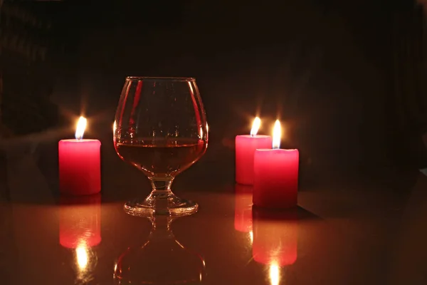 Glass of brandy or cognac and candle on the wooden table — Stock Photo, Image