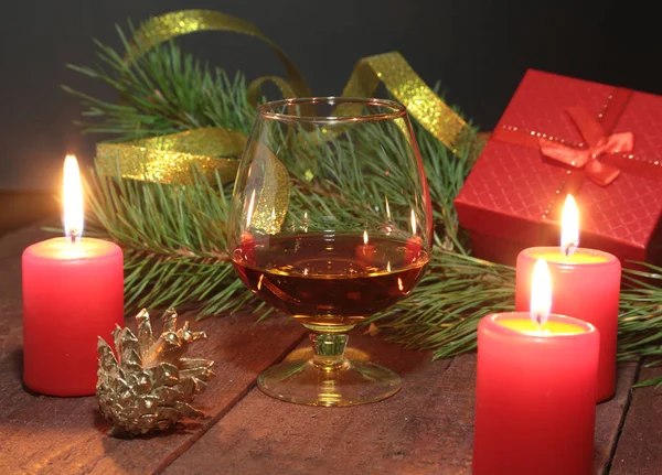 Bicchiere di brandy e candele su sfondo nero — Foto Stock