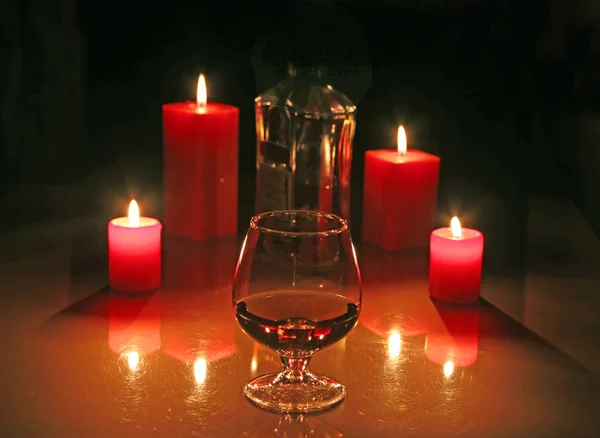 Brandy Glas und Kerzen auf schwarzem Hintergrund — Stockfoto