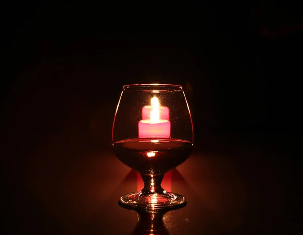 Brandy glass and candles on black background — Stock Photo, Image