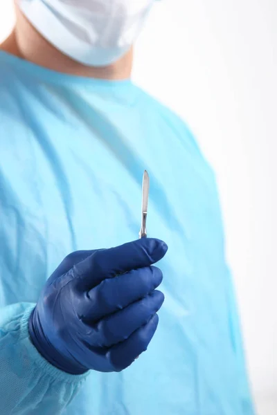 Homem cirurgião segura um bisturi em uma sala de cirurgia — Fotografia de Stock