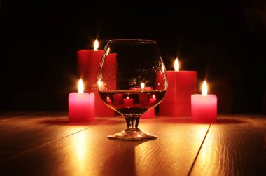 konyak ve kırmızı mum ahşap arka plan üzerinde bardak.