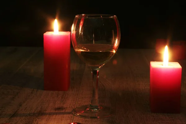 Kieliszek wina lub koniak i czerwona świeca na podłoże drewniane. — Zdjęcie stockowe