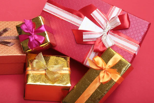 Beautiful gold present box with red bow and ribbons on  backgound