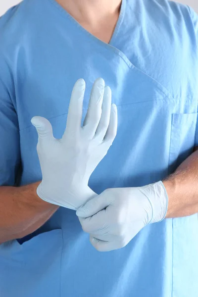 Arzt zieht sterile Handschuhe isoliert weiß an — Stockfoto