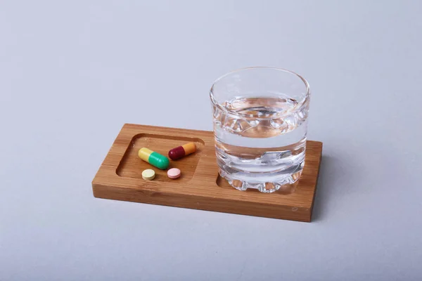 Vaso de agua y pastillas sobre fondo blanco —  Fotos de Stock