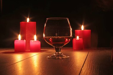 Bardak brendi veya konyak ve ahşap masa mum