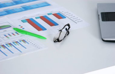 Dizüstü bilgisayar, gözlük, kahve fincanı, not defterleri ve diğer öğeler bulanık şehir arka plan üzerinde beyaz masaüstü closeup