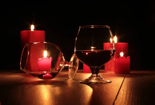 Vaso de brandy o coñac y vela sobre la mesa de madera — Foto de Stock