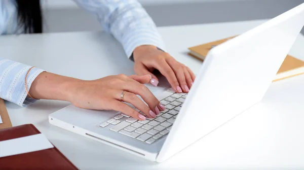 Жінка працює на ноутбуці, сидячи за столом — стокове фото