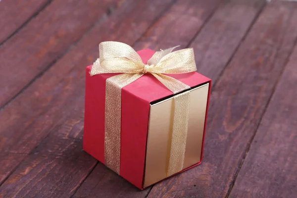 Belle boîte cadeau en or, rouge et rubans sur fond — Photo