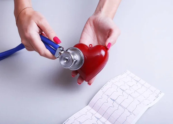 Female medicine doctor hold in hands red toy heart and stethoscope head. Cardio therapeutist, student education, physician make cardiac physical, rate measure, arrhythmia concept — Stock Photo, Image