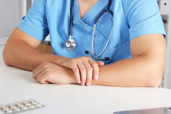 Retrato de um médico com estetoscópio senta-se à mesa . — Fotografia de Stock