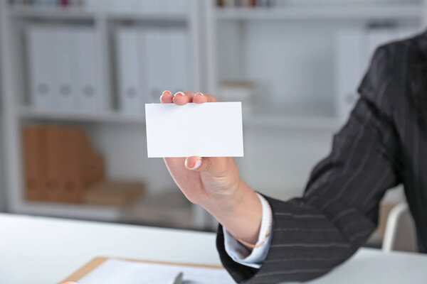Деловая женщина с пустой визитной карточкой, сидит на столе

