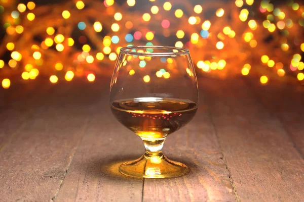 Glass of cognac, brandy or whiscy on mirror table. bottles in a bar on the background — Stock Photo, Image