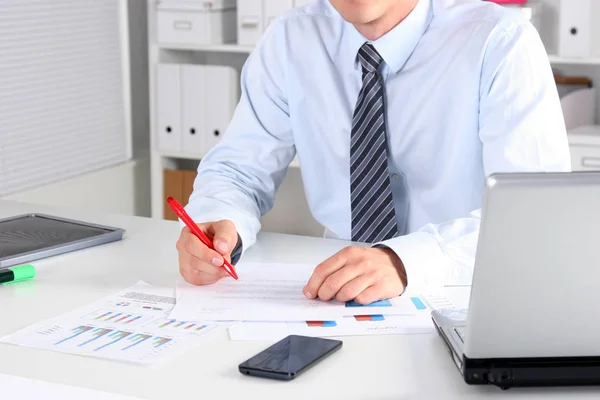 Cheerful young businessman sitting at the table with laptop and stretching in the office Stock Image