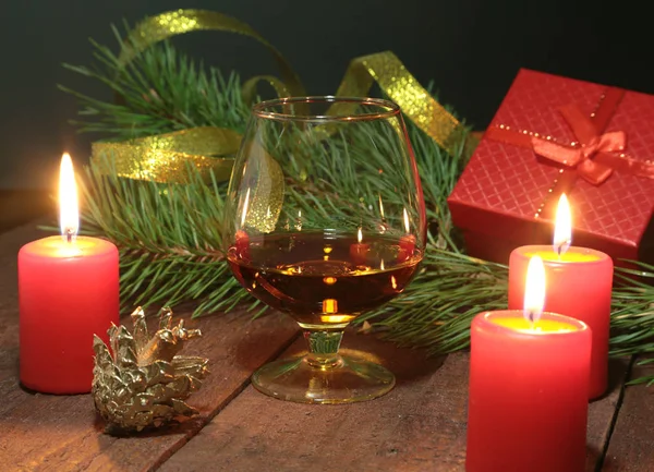 Ποτήρι κονιάκ ή κονιάκ, κιβώτιο δώρων και κερί πάνω στο ξύλινο τραπέζι. Γιορτή σύνθεση. — Φωτογραφία Αρχείου