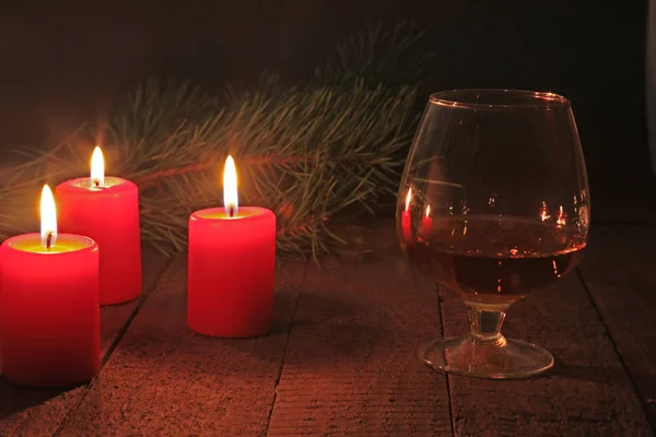 Bicchiere di brandy o cognac e candela sul tavolo di legno. Composizione della celebrazione . — Foto Stock